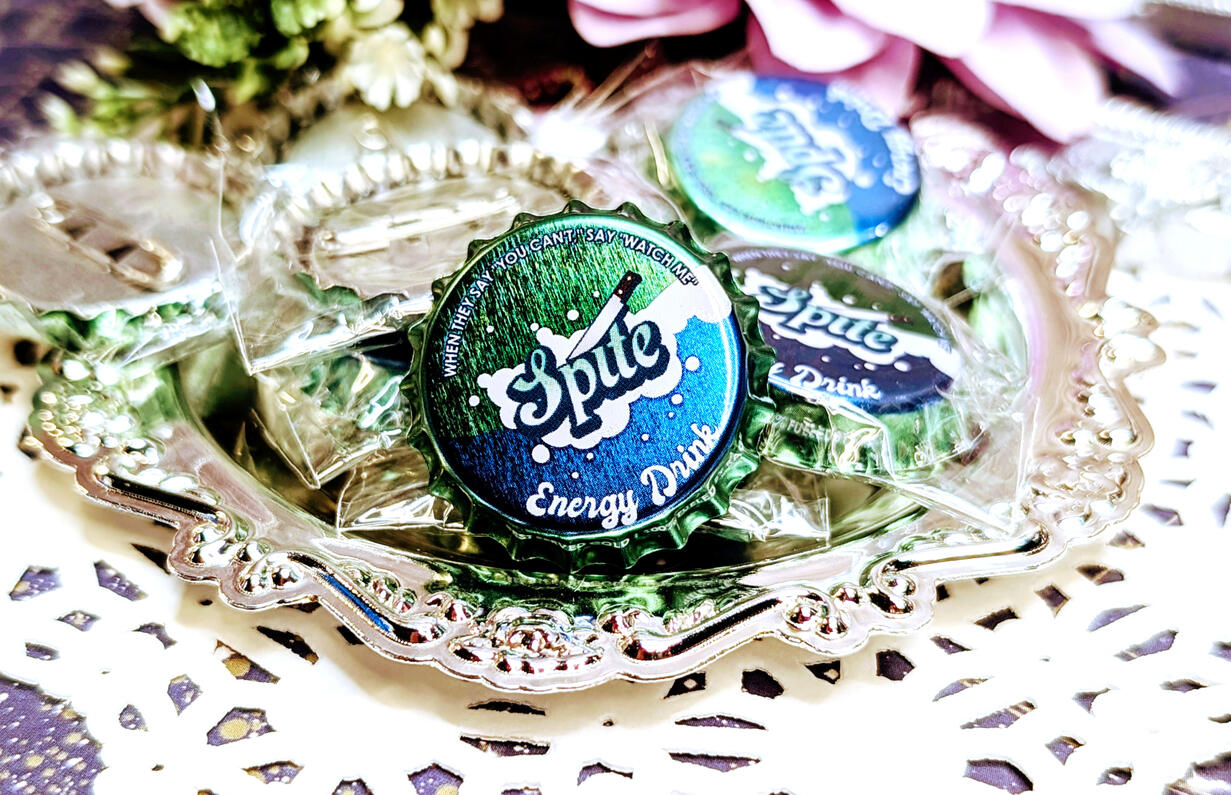metallic bottle cap button featuring a blue green design with the word SPITE on it.